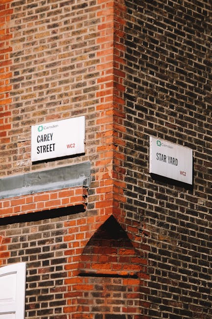 A photograph of the corner of two brick buildings featuring street signs, with a focus on the brickwork and signage. The left side displays a white sign with green accents reading 'Carey Street' and the right side shows a similar sign reading 'Star Yard,' both mounted on dark-colored bricks. The brick surfaces are clean and well-maintained, with visible mortar joints and a mixture of red and brown tones. The lighting appears natural, highlighting the texture and color of the bricks, and the signage is clear and legible. Camden Carpet Cleaning emphasizes surface and building maintenance, and this image reflects the importance of clean and well-kept exteriors.